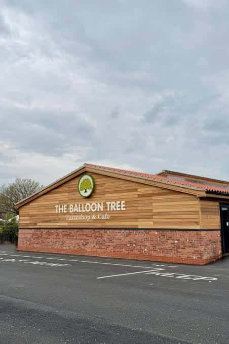 Fachada exterior del The Balloon Tree Farm Shop & Cafe con su distintivo letrero