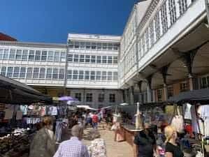 Interior del mercado con puestos y gente caminando bajo el sol