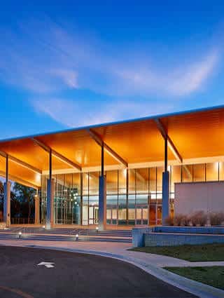 Fachada exterior del St. Andrew's Dell Fine Arts Center al atardecer con iluminación cálida