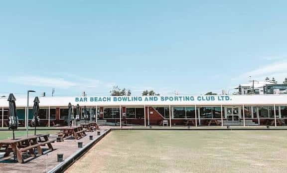 Vista exterior del Bar Beach Bowling & Sporting Club con césped de bolos y mesas al aire libre