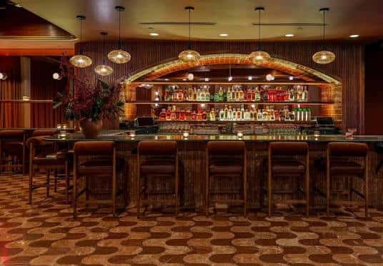 Interior del bar Foxtail en Austin con barra de ladrillo y estantería iluminada