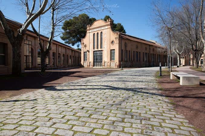 Vista exterior de la fachada principal de la Fábrica de Armas con su arquitectura industrial y camino empedrado
