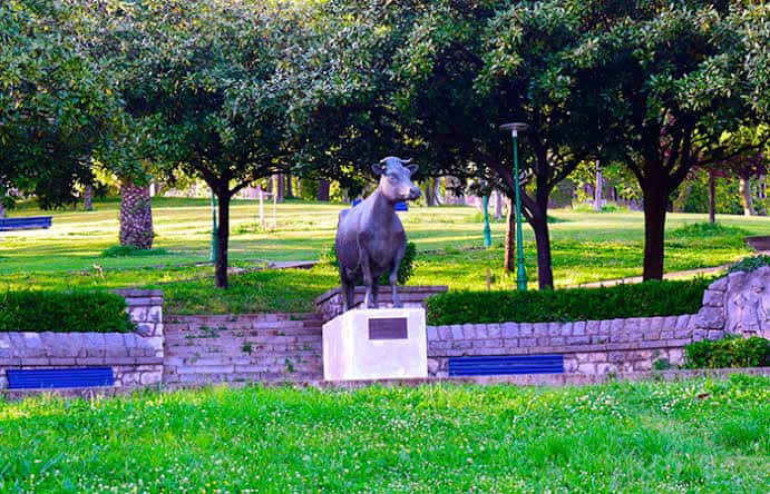 Estatua de la vaca en el Parque del Doctor Morales con césped y árboles al fondo