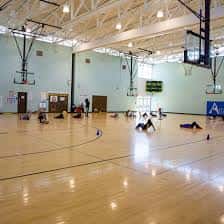 Gimnasio interior del centro recreativo con canchas de baloncesto y personas realizando actividades