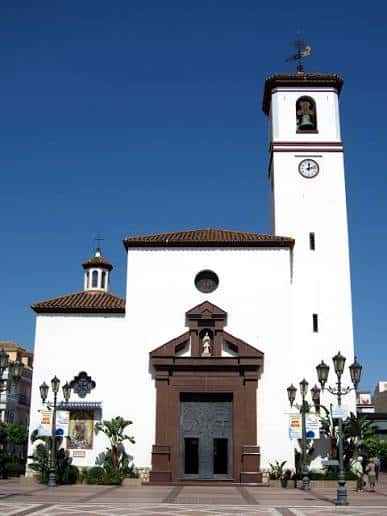 Fachada principal de la Parroquia de Nuestra Señora del Rosario en Fuengirola con torre y cielo despejado
