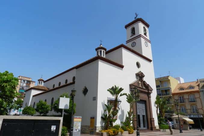 Vista lateral exterior de la parroquia mostrando su arquitectura blanca y entorno urbano