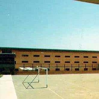 Patio exterior del centro penitenciario con cancha deportiva y edificio de ladrillo