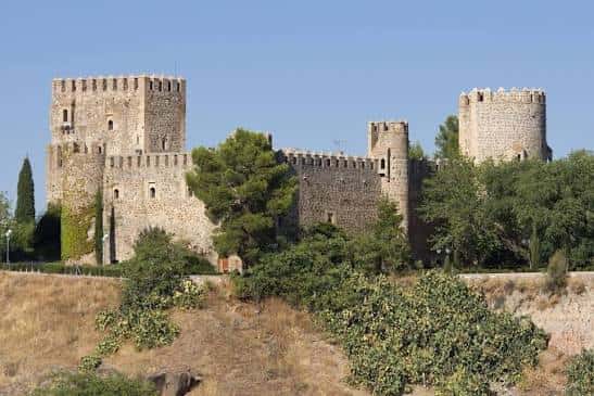 Fachada principal del castillo con torres y muros de piedra bajo cielo despejado