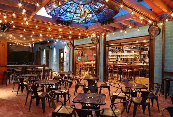 Terraza interior con techo de vitrales, luces colgantes y mesas dispuestas para eventos