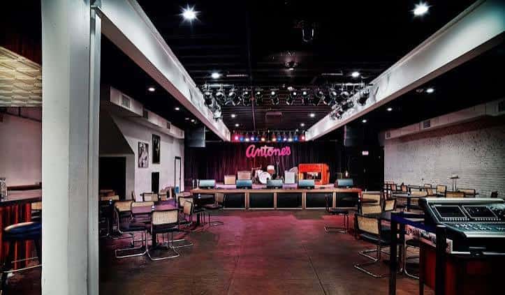 Interior del club Antone's mostrando el escenario con iluminación y mesas de trabajo