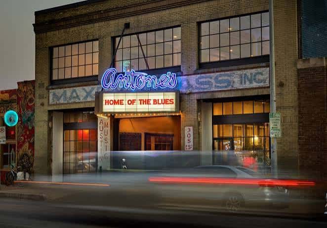 Fachada exterior nocturna de Antone's con letrero luminoso 'Home of the Blues'