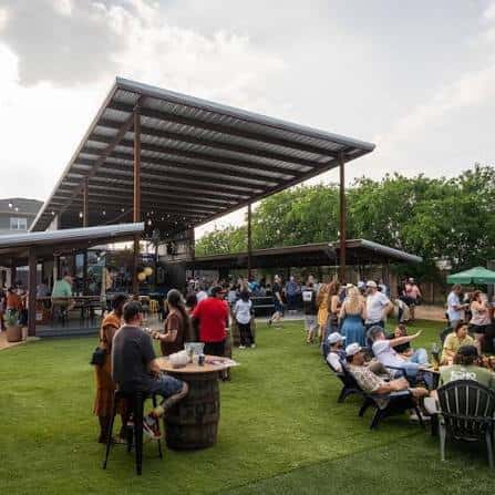 Patio principal con césped artificial, toldo grande y grupo de personas socializando