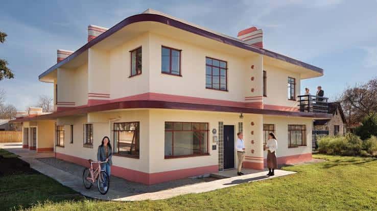Fachada principal de la casa durante el día con personas visitando el lugar