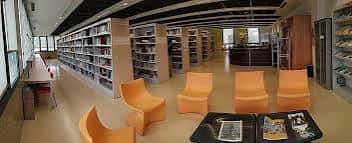 Interior de la biblioteca del Centro Cultural Unicaja con estanterías y sillas naranjas