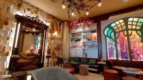 Interior acogedor con decoración artística, estanterías, espejo antiguo y ventana colorida