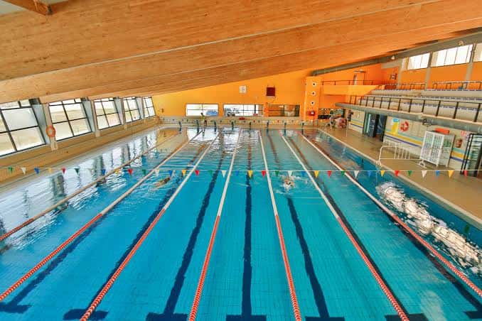 Piscina cubierta con carriles marcados y espectadores en las gradas