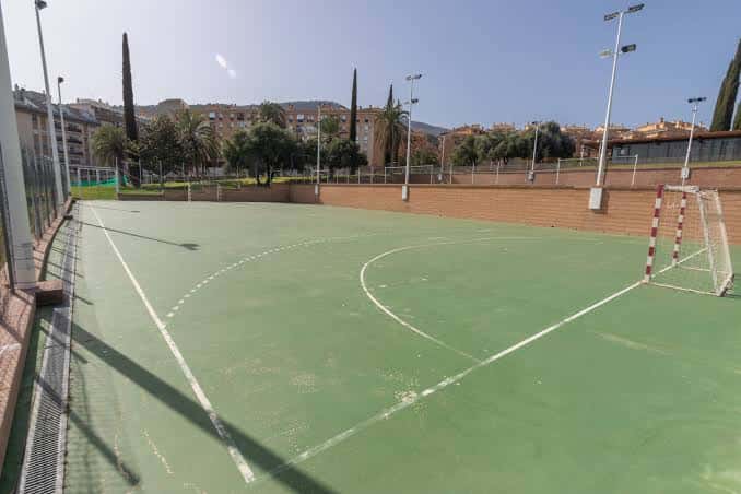 Campo de fútbol sala con portería y entorno urbano al fondo