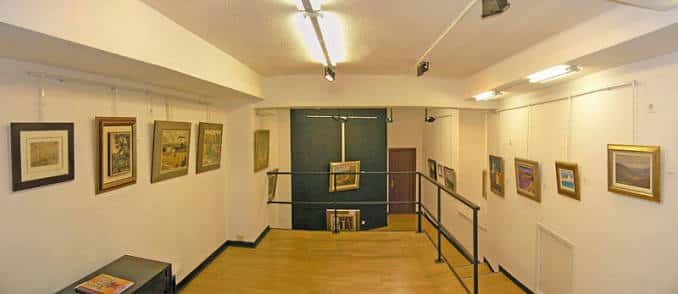 Vista panorámica del interior de la galería de arte con cuadros colgados en las paredes