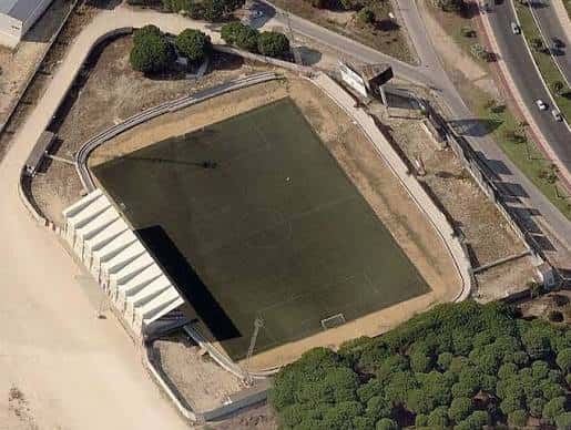Vista aérea del campo de fútbol y estructura del estadio rodeado de vegetación