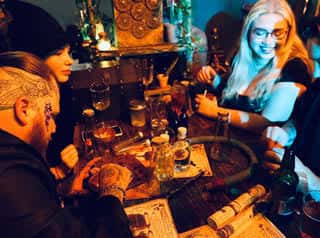 Grupo de personas disfrutando de bebidas en el Dark Arts Bar con ambiente místico