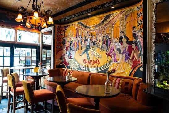 Sala de estar con murales coloridos estilo cabaret y mesas para eventos
