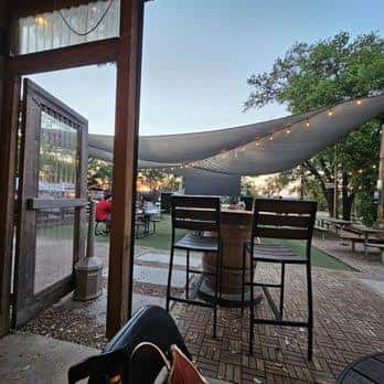 Terraza exterior del bar con mesas altas y toldo decorativo