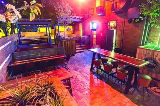 Terraza al aire libre con mesas altas y ambiente festivo nocturno