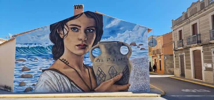 Vista del mural de la calle Els Poblets mostrando una mujer con un jarrón y el mar de fondo