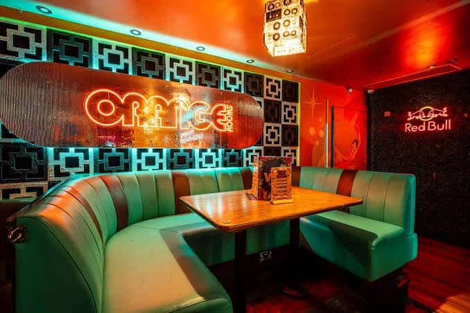 Zona de mesas con sofás verdes y decoración retro estilo años 50