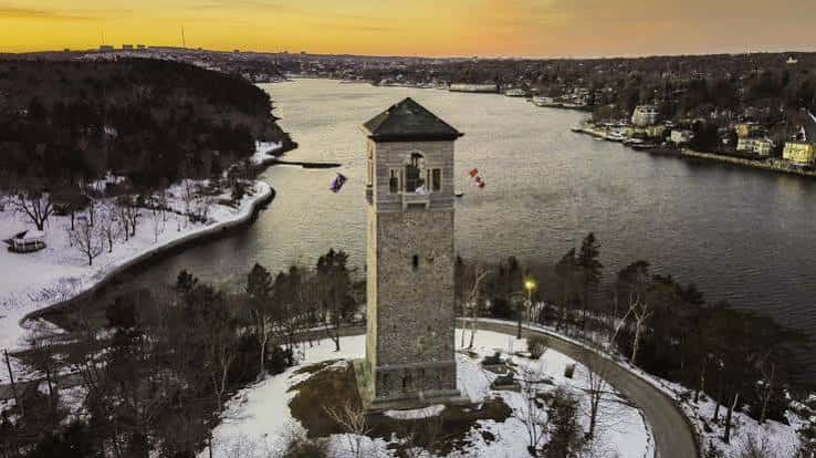 Vista aérea de la Torre Memorial durante el atardecer invernal con nieve y banderas canadienses