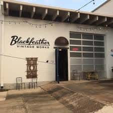 Fachada exterior de Blackfeather Vintage Works con letrero y luces decorativas