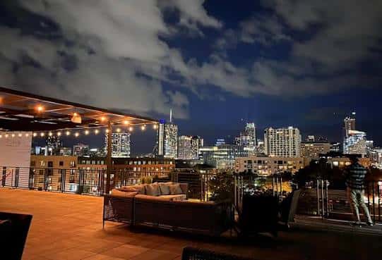 Terraza en la azotea con vistas nocturnas a la ciudad y zona de estar