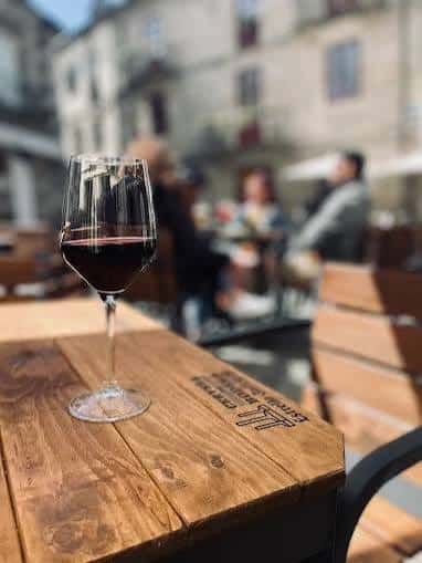 Detalle de mesa en terraza con copa de vino tinto y ambiente relajado