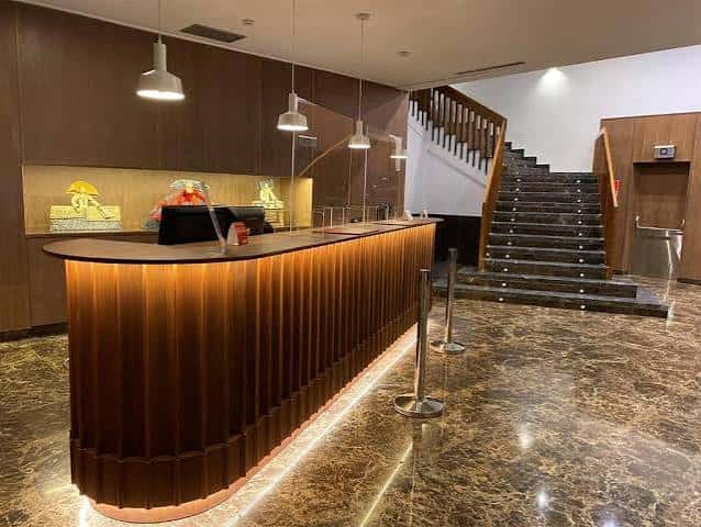 Recepción del hotel con mostrador de madera y escalera al fondo