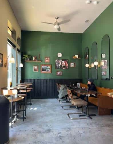 Espacio interior moderno de Klerje Coffee con paredes verdes y decoración minimalista