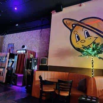 Interior del club con mural de un planeta sonriente y zona de juegos retro