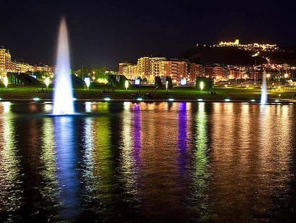 Vista nocturna del Parque del Bulevar con fuentes iluminadas y reflejos en el agua