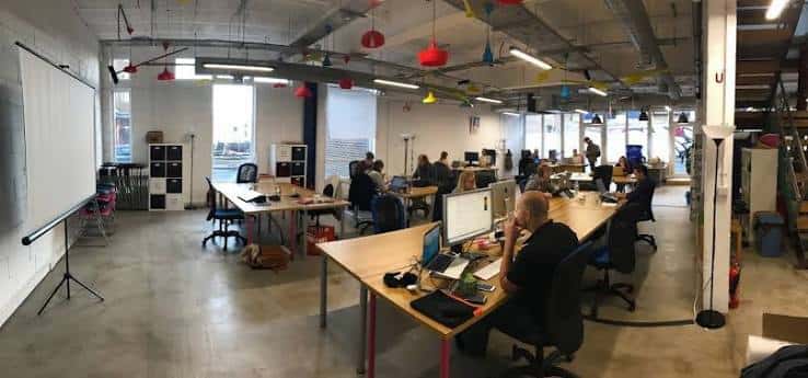 Interior del espacio de coworking The Skiff en Brighton con mesas y personas trabajando