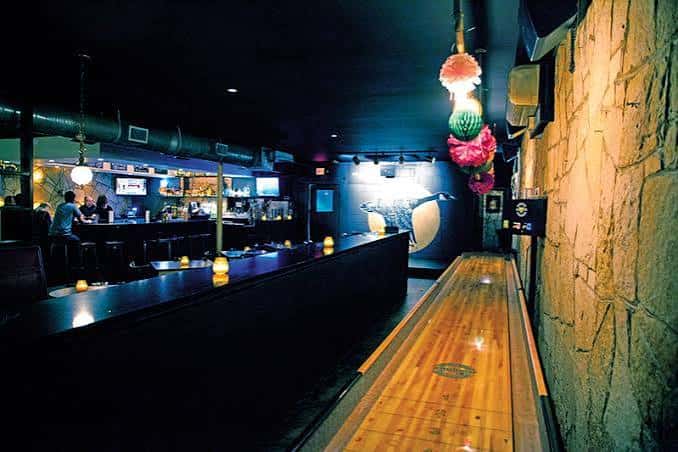 Interior del bar con pista de shuffleboard y ambiente nocturno