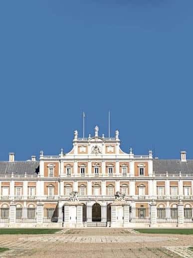 Primer plano de la entrada principal del palacio con esculturas y bandera
