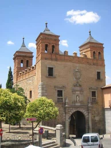 Puerta del Cambrón bajo un cielo azul con nubes y árboles verdes al frente