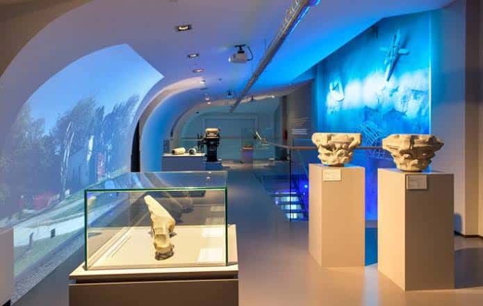 Interior del museo con exhibiciones arqueológicas e iluminación ambiental azul