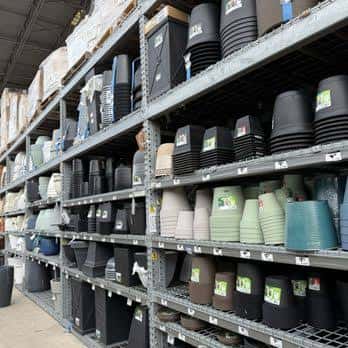 Pasillo interior de la tienda mostrando macetas y productos de jardinería organizados en estanterías