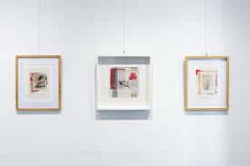 Vista interior de la galería con obras expuestas en pared blanca