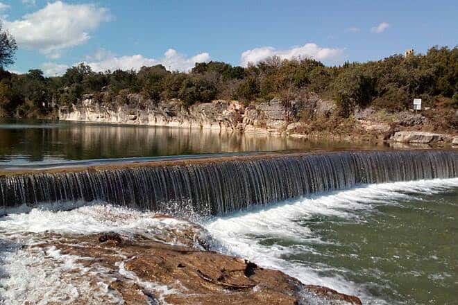Vista panorámica del río con una presa de agua y vegetación en el fondo