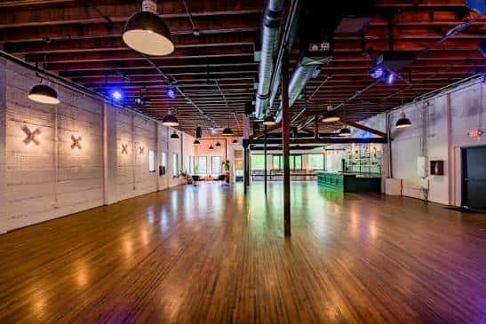 Vista panorámica del salón principal con suelo de madera y techo industrial
