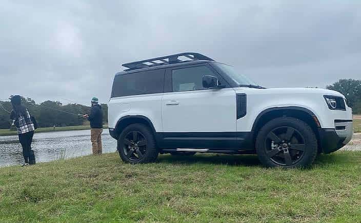 Land Rover Defender blanco estacionado junto a un lago