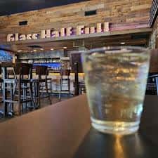 Vista del interior del bar con letrero 'Glass Half Full' y vaso en primer plano
