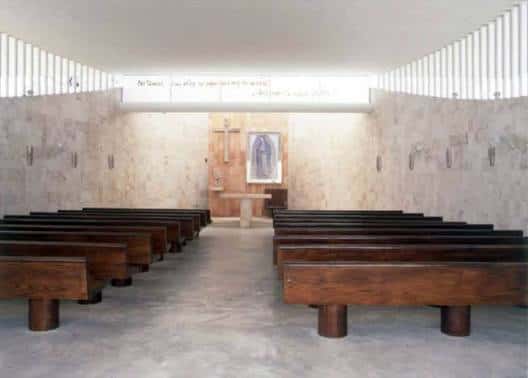 Interior de la capilla mostrando el altar y las bancas de madera