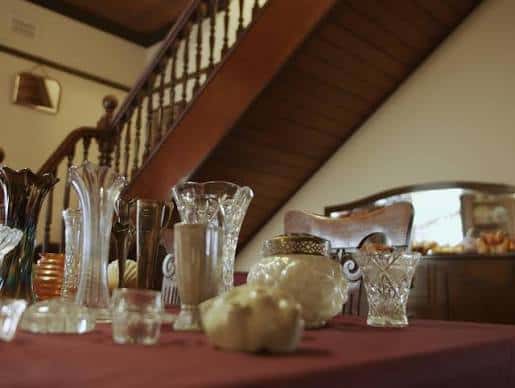 Detalle de cristalería y objetos decorativos sobre una mesa en el interior del museo